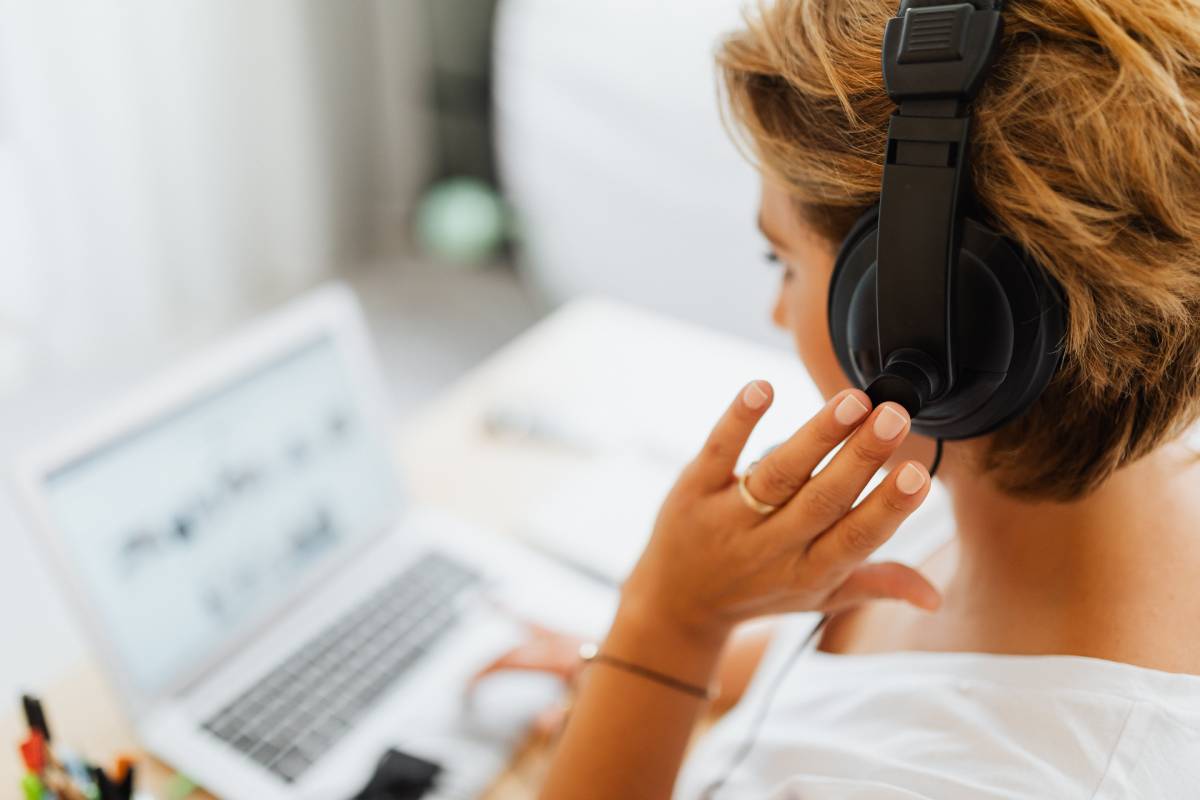 A business woman using a headset and a laptop to communicate with co-workers