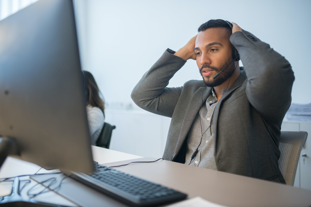 A bearded contact center employees looking at the screen of a computer