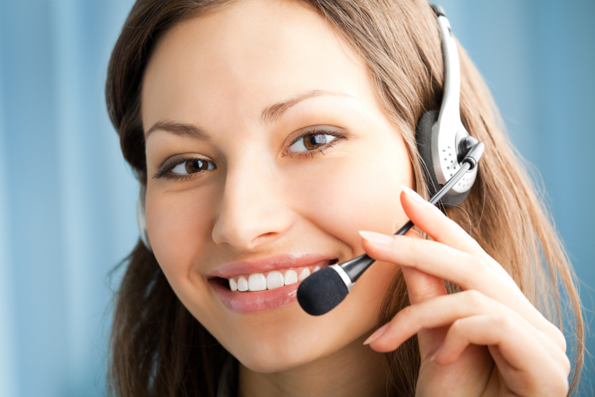 Contact center representative wearing a headset smiles into camera.