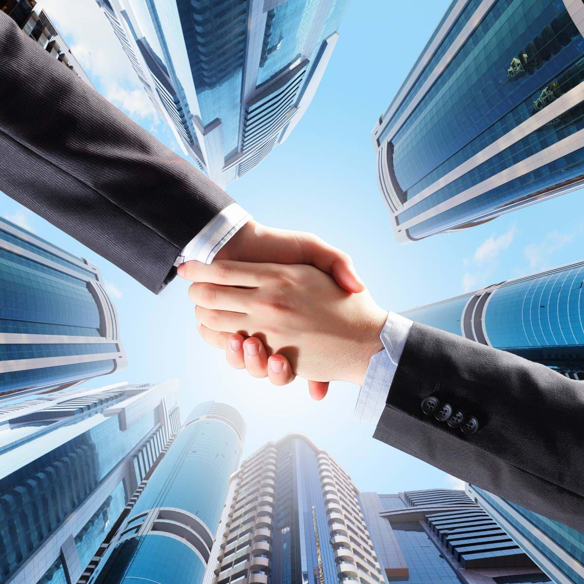 Two businessmen shaking hands with buildings in the background