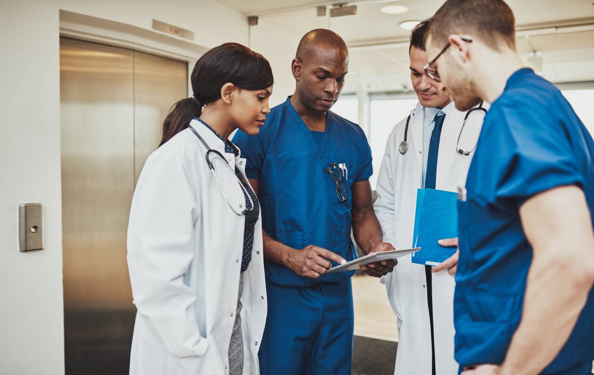 A group of doctors talking while using a tablet