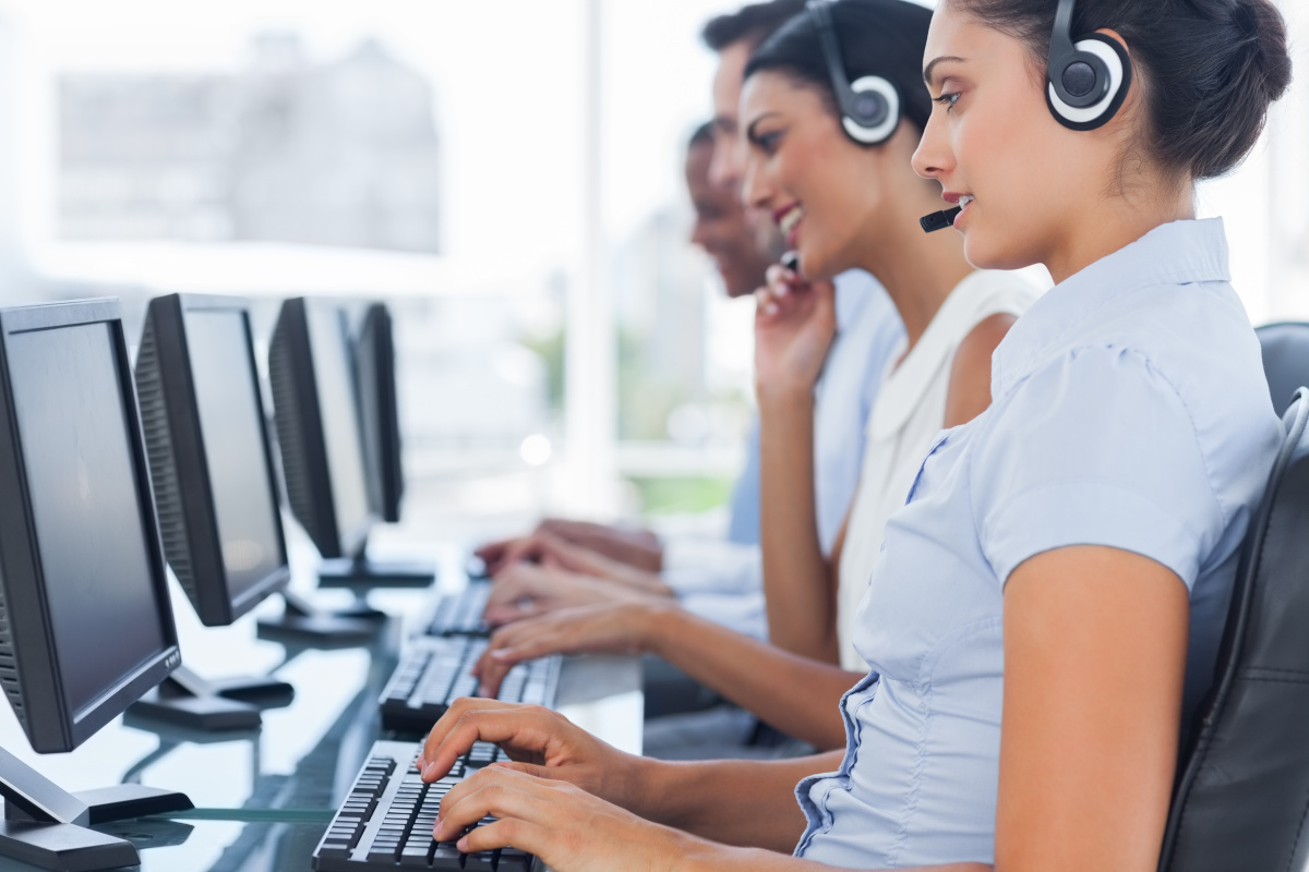 Help desk employees using headsets and computers to assist customers