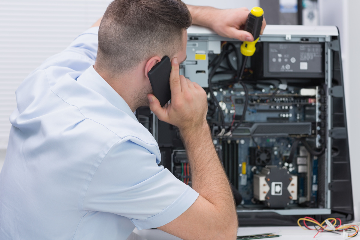 A person on a phone attempting to fix the hardware of a computer