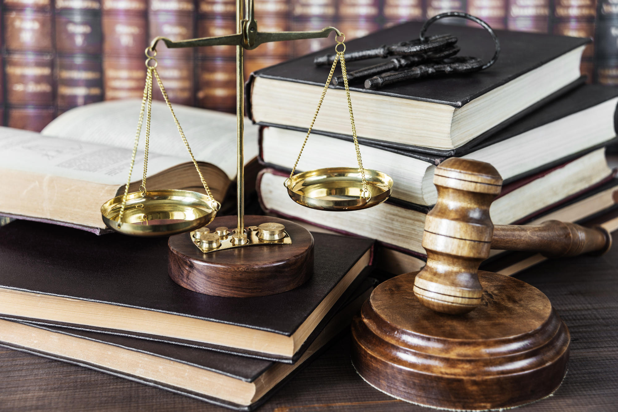 Stack of legal books on desk with a scale of justice and a judge's gavel